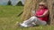 Woman with white smartphone sits near haystack and listening to music