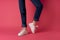 woman in white sneakers legs pink background posing