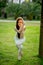 Woman in white sports outfit performing Yoga Eagle pose outdoor, in park meadow.