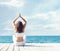 Woman in white sportswear doing yoga on a wooden pier. Sea and sky background. Yoga, sport, vacation and travelin