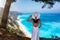 A woman in a white summer dress enjoys the view to the blue sea of Egremni Beac