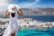 A woman in a white summer dress enjoys the view to the windmills of Mykonos town, Greece