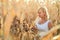 Woman in a white summer long dress walks on a cornfield and posing in sunset time