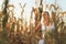 Woman in a white summer long dress walks on a cornfield and posing in sunset time