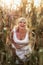 Woman in a white summer long dress walks on a cornfield and posing in sunset time