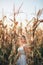 Woman in a white summer long dress walks on a cornfield and posing in sunset time