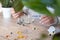 a woman in a white sweater adds drops of chlorophyll to a glass of water standing next to palm trees