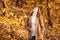 Woman in white sweater and beige jacket in autumn park. Happy adult girl walking in autumn forest