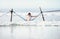 Woman in white swimsuit sits in hammock swing over the ocean surf line