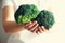 Woman in white T-shirt holding broccoli in hands. Copy space. Healthy clean detox eating concept. Vegetarian, vegan, raw