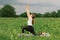 Woman in a white T-shirt and leggings doing yoga in a beautiful field on a sports mat. lifestyle and mindfulness concept