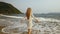 Woman in a white tunic on the beach, near the stormy sea. Blonde