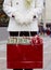 Woman in white wool coat and gloves holding shopping bag with Christmas gifts presents wrapped in festive wrapping paper and bows