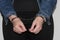 A woman who has been arrested and has her hands handcuffed as she awaits transport