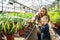 Woman who works in the greenhouse teaches her son to water the plants.