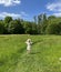 Woman on wild field with blossom yellow flowers and bright sky with white clouds summer nature landscape, gree