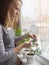 Woman at the window with a plant pomegranate. Caring for houseplants in the winter.