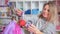 a woman winds a nozzle on a balloon with helium to inflate foil balls.