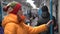 A woman in winter clothes rides in a train car and holds on to the handrail