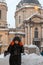 woman in winter coat walking by city street after snowstorm