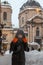 woman in winter coat walking by city street after snowstorm