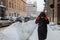 woman in winter coat walking by city street after snowstorm