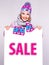 Woman in winter outerwear holds the white banner with sale word