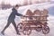 A woman in winter rolls a cart with hay