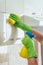 A woman wipes a yellow cloth kitchen cabinet, using a chemical from a bottle. Cleaning of the apartment. Light kitchen. kitchen