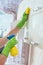 A woman wipes yellow cloth kitchen cabinets, applying the chemical with a bottle. cleaning of the apartment