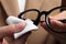 Woman wiping her glasses with microfiber cloth, closeup