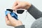 Woman wiping sunglasses with cleaning cloth on light background, closeup