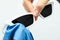 Woman wiping sunglasses with microfiber cleaning cloth on light background