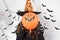 A woman in a witch costume in a hat holds a ball pumpkin. Halloween people.