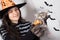 A woman in a witch costume holds a kitten and a candle in the form of a pumpkin. Halloween people and animals.