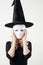 Woman in witch costume putting on plastic white mask