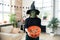 Woman in witches costume holding bucket of treats