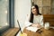 Woman work in cafe with laptop near window with coffee latte