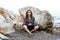 Woman workaholic working on a laptop while sitting on a rock on the beach