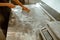 Woman worker cleans metal table from flour in modern craft bakery workshop