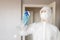 Woman worker disinfects surface of house from infection with virus and microbes in biochemical suit