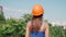 Woman worker in hard hat on the background of the city on a summer sunny day. Girl trainee builder getting ready to start working