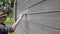 Woman worker painting wooden house exterior wall with paintbrush and wood protective color