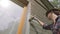 Woman worker painting wooden house exterior wall with paintbrush and wood protective color