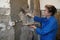 Woman worker plastering concrete at wall of house