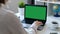 Woman working on a computer, green screen. Over the shoulder shot