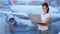 Woman working on computer near window at airport, blurred airplane on background