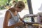 Woman working with glue pistol, view from above mounting seashells on a wooden mirror frame, hand made manufacture