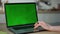 Woman working greenscreen laptop at kitchen close up. Hands scrolling touchpad.
