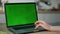 Woman working greenscreen laptop at kitchen close up. Hands scrolling touchpad.